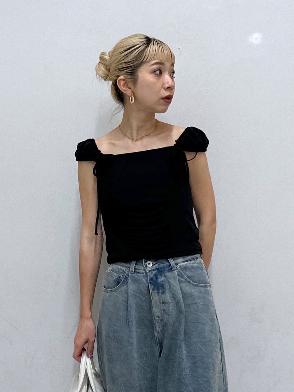 ブラック系のTシャツ/カットソー、ブルー系のデニムパンツ、ゴールド系のパンプスを着用したレディースの春コーディネートの4枚目の写真