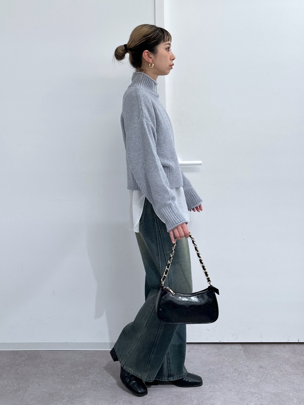 グレー系のニット/セーター、ホワイト系のTシャツ/カットソー、ブルー系のデニムパンツを着用したレディースの冬コーディネートの2枚目の写真