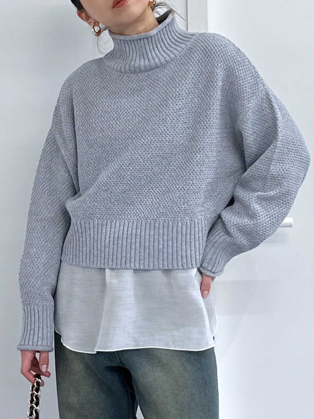 グレー系のニット/セーター、ホワイト系のTシャツ/カットソー、ブルー系のデニムパンツを着用したレディースの冬コーディネートの4枚目の写真