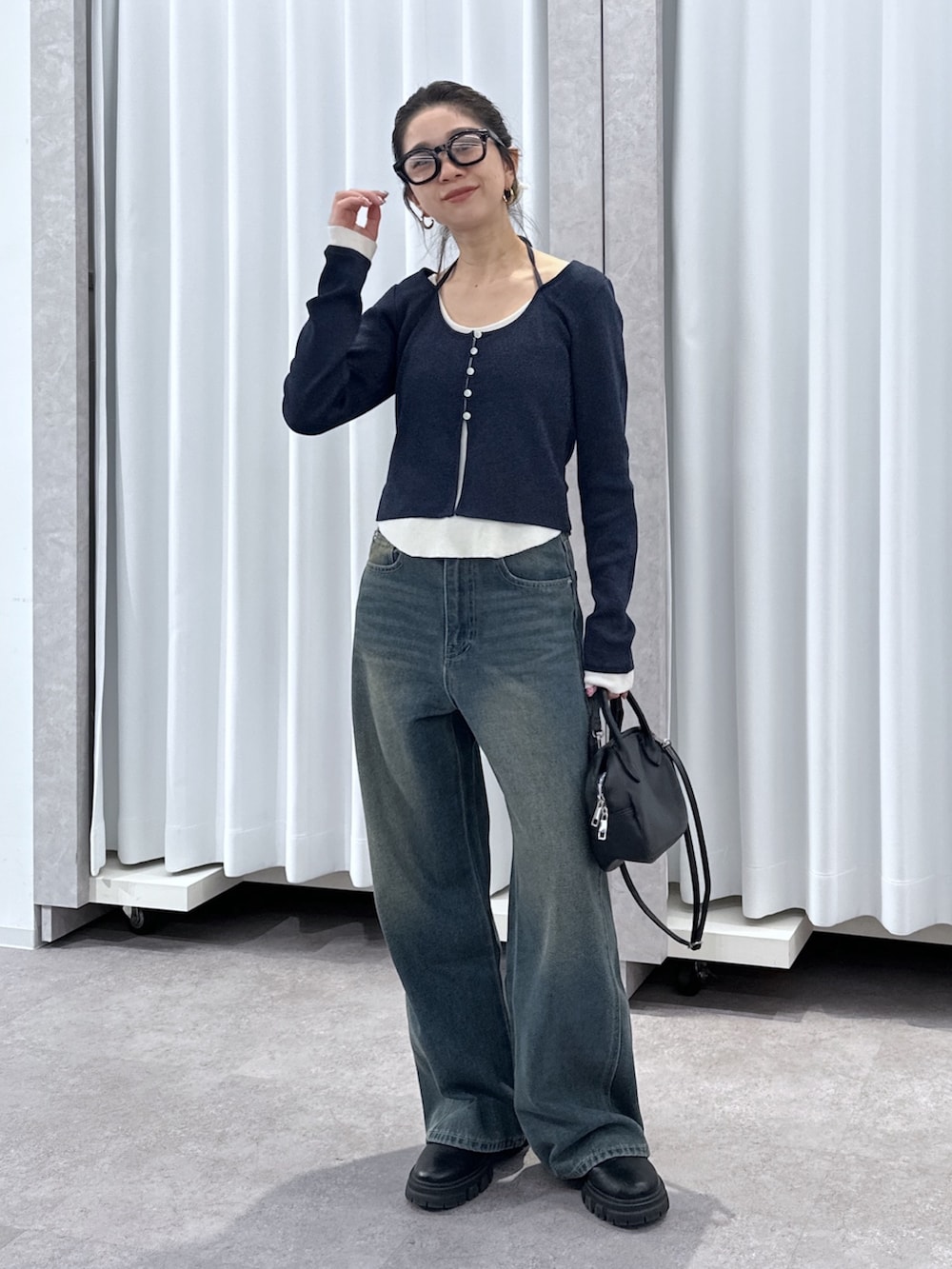 ブルー系のニット/セーター、ブルー系のデニムパンツ、ブラック系のハンドバッグを着用したレディースの春コーディネートの9枚目の写真