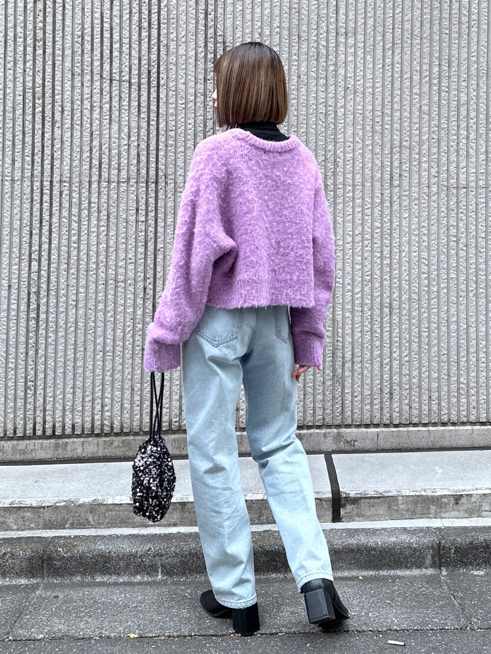 パープル系のニット/セーター、ブルー系のデニムパンツ、ブラック系のハンドバッグを着用したレディースの冬コーディネートの4枚目の写真