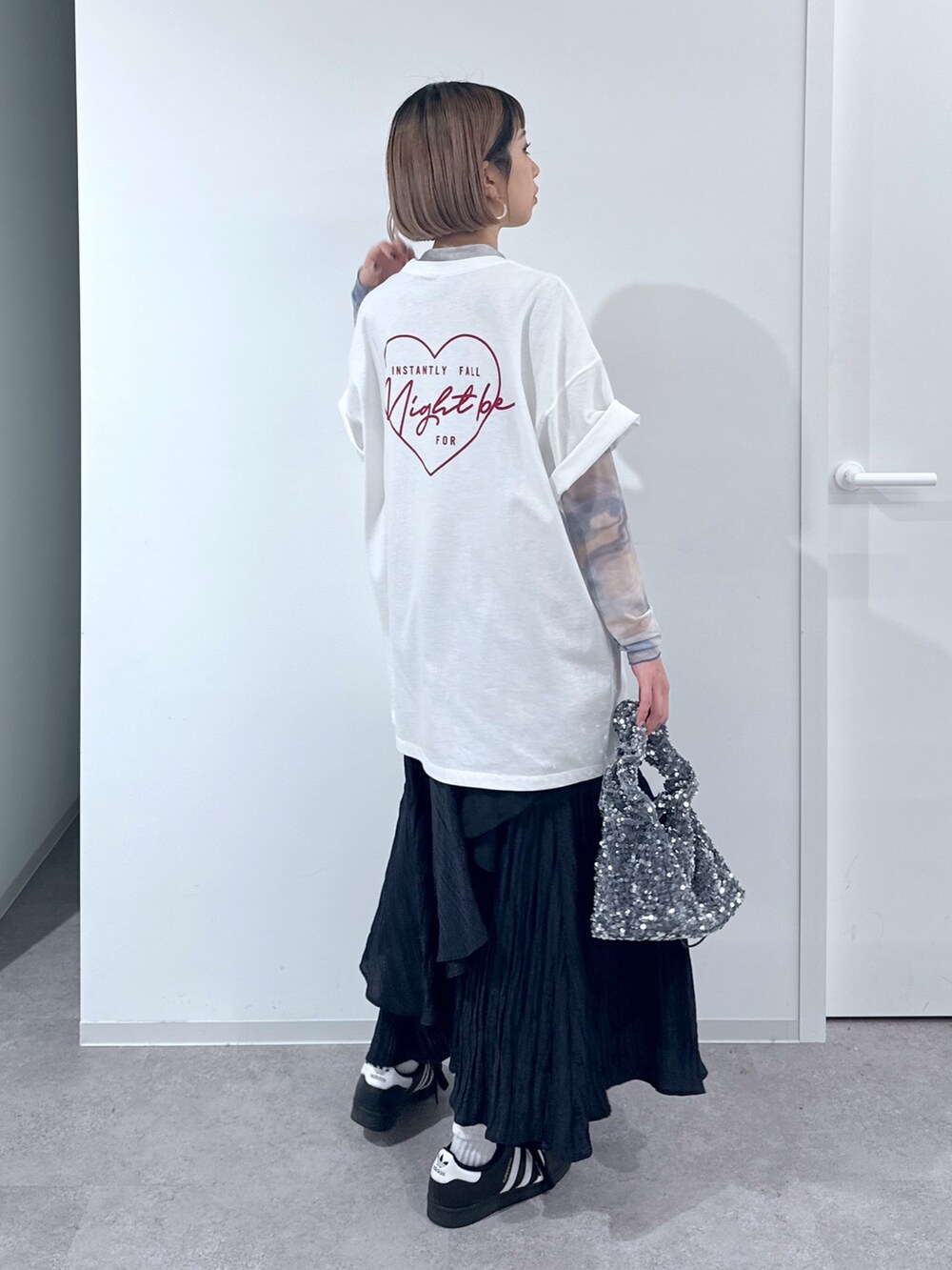 ホワイト系のTシャツ/カットソー、オレンジ系のTシャツ/カットソー、ブラック系のスカートを着用したレディースの春コーディネートの3枚目の写真