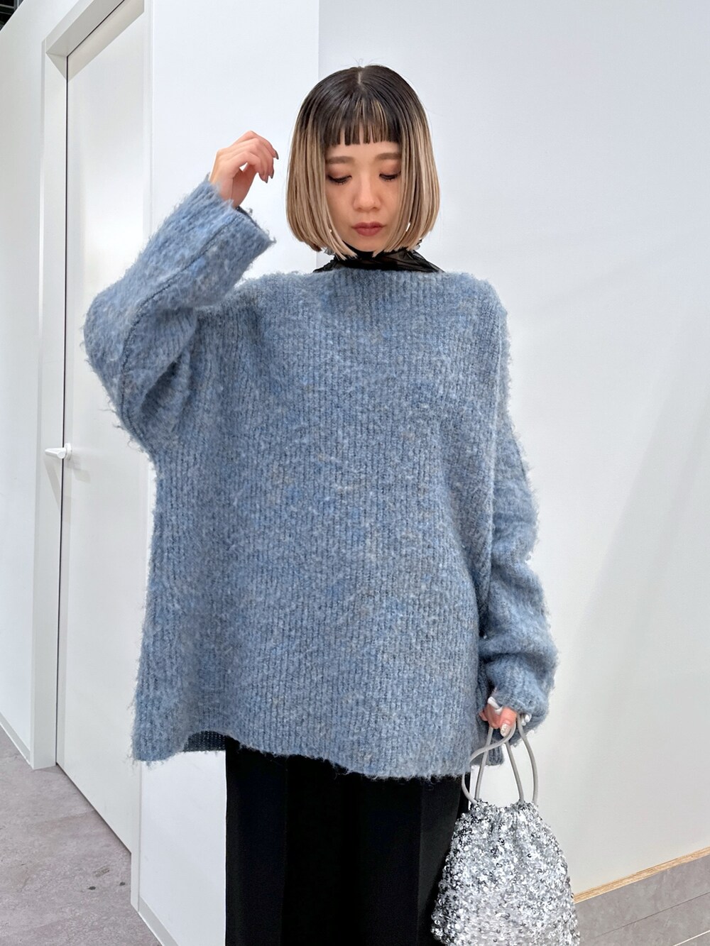 ブルー系のニット/セーター、ブラック系のTシャツ/カットソー、ブラック系のスラックスを着用したレディースの冬コーディネートの4枚目の写真