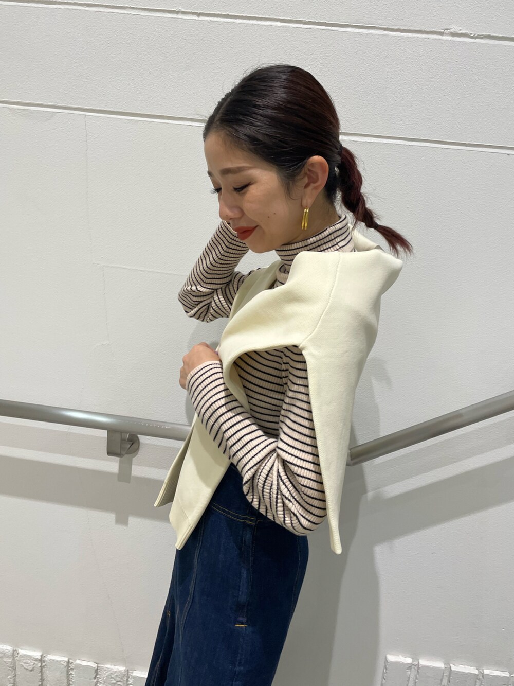 ブルー系のデニムスカート、ホワイト系のニット/セーター、ホワイト系のブーツを着用したレディースの秋コーディネートの3枚目の写真