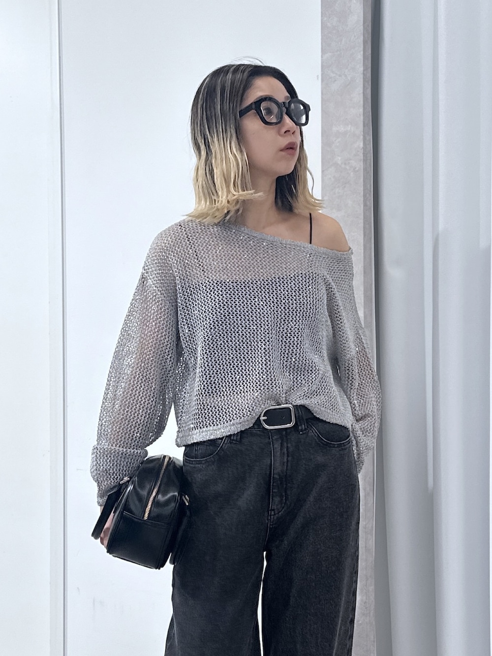 ブラック系のデニムパンツ、グレー系のニット/セーター、ブラック系のキャミソールを着用したレディースの春コーディネートの4枚目の写真