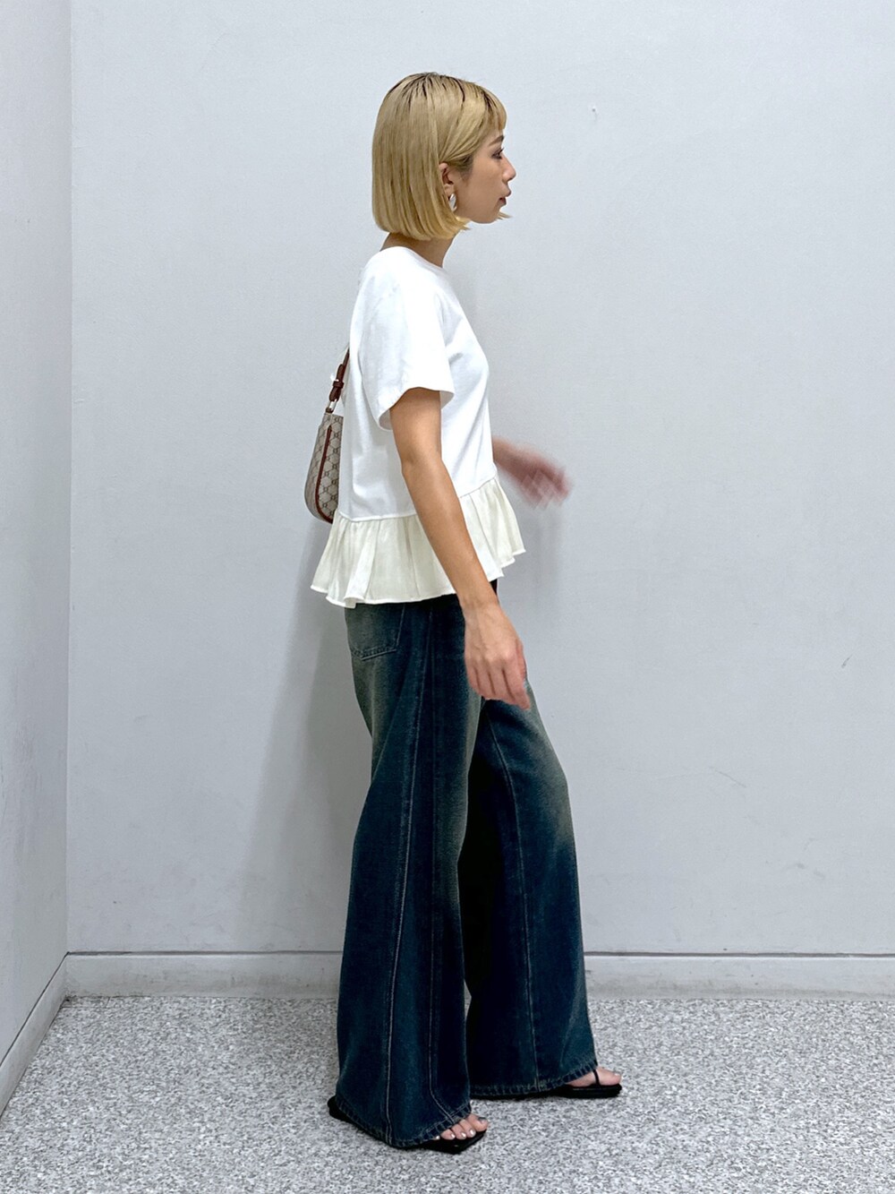 ブルー系のデニムパンツ、ホワイト系のTシャツ/カットソー、ベージュ系のショルダーバッグを着用したレディースの夏コーディネートの2枚目の写真