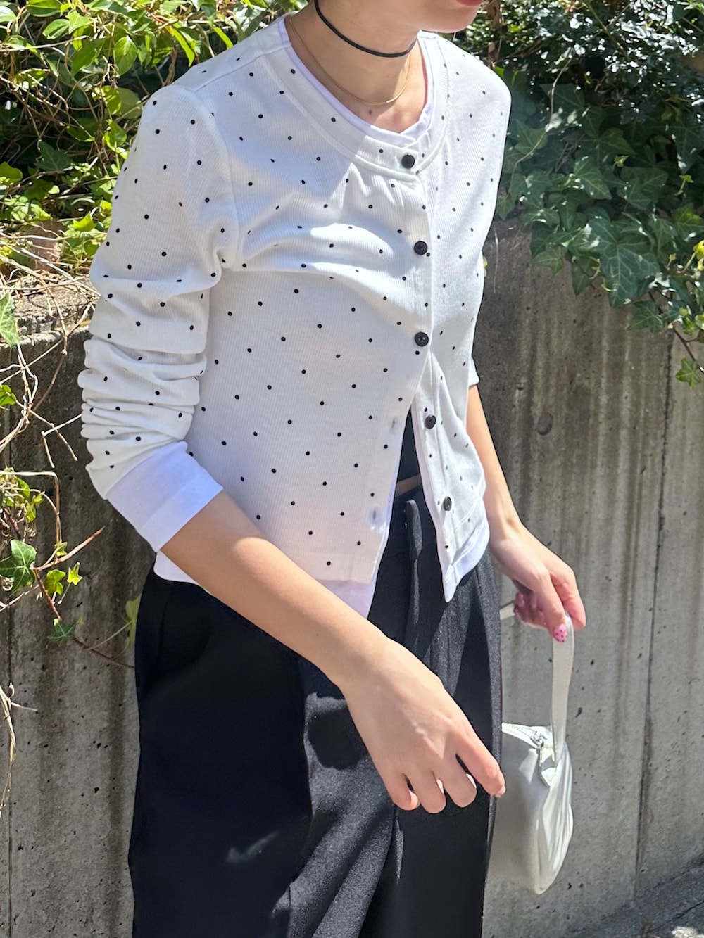 ホワイト系のTシャツ/カットソー、ブラック系のスラックス、ホワイト系のハンドバッグを着用したレディースの春コーディネートの5枚目の写真