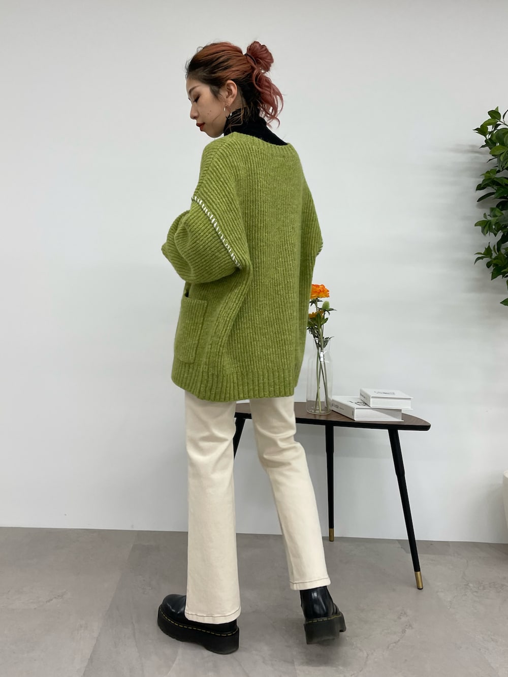 ホワイト系のデニムパンツ、グリーン系のカーディガン/ボレロ、ブラック系のニット/セーターを着用したレディースの秋コーディネートの2枚目の写真