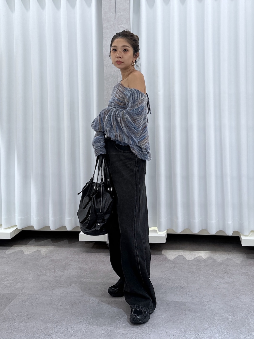 ブルー系のニット/セーター、ブラック系のデニムパンツ、ブラック系のショルダーバッグを着用したレディースの夏コーディネートの2枚目の写真
