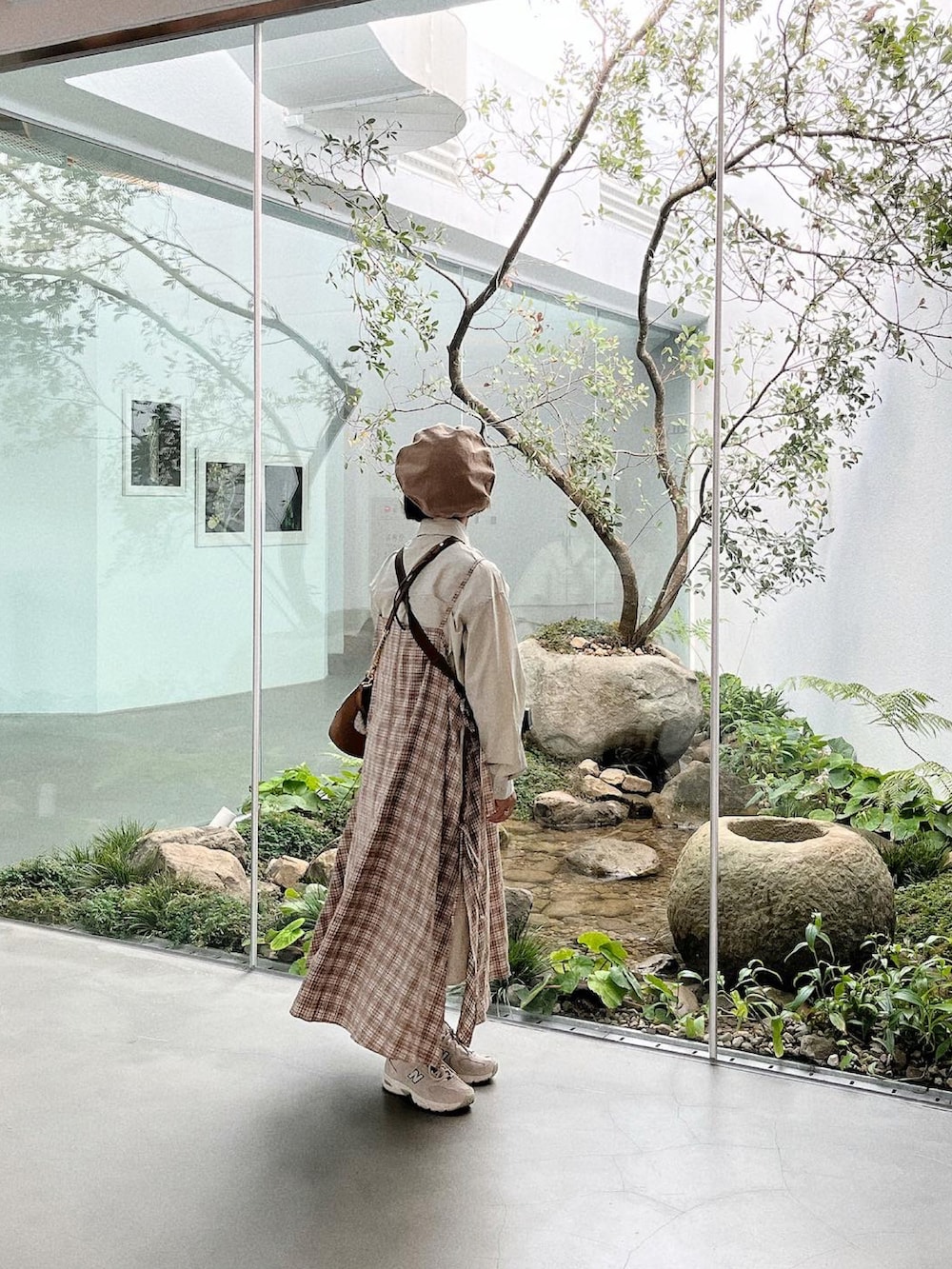 グレー系のスニーカー、ベージュ系のドラムバッグ、ベージュ系のジャンパースカートを着用したレディースの秋コーディネートの2枚目の写真