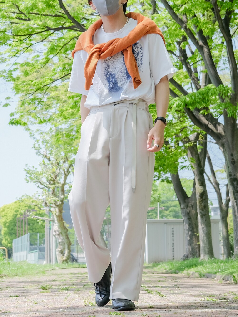 オレンジ系のカーディガン/ボレロ、ベージュ系のスラックス、ブラック系のドレスシューズを着用したメンズの春コーディネートの2枚目の写真