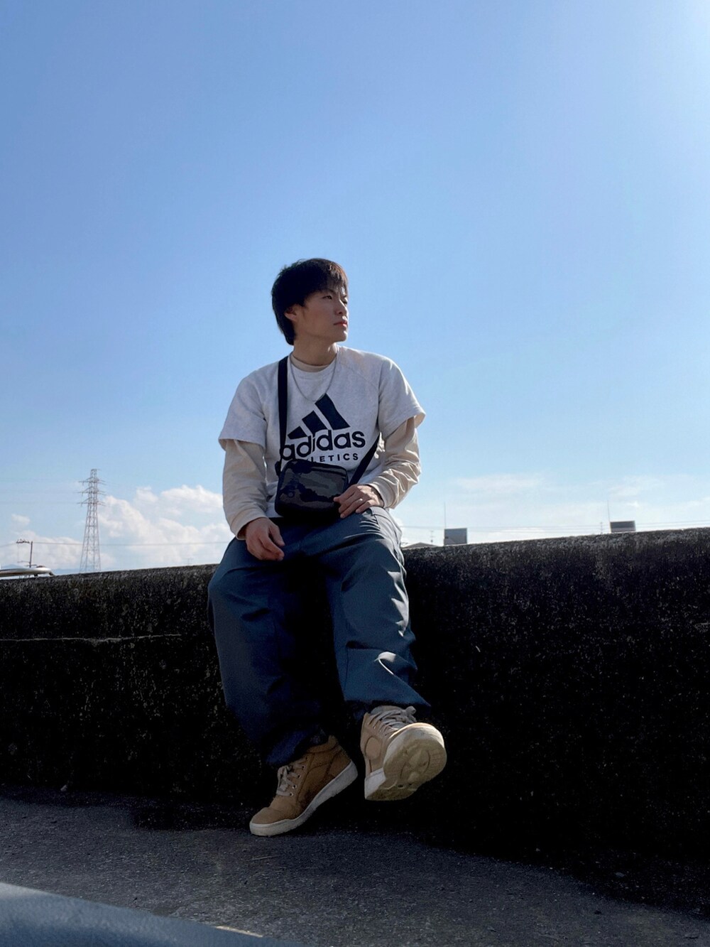 ブラック系のショルダーバッグ、ホワイト系のTシャツ/カットソー、ベージュ系のTシャツ/カットソーを着用したメンズの春コーディネートの2枚目の写真