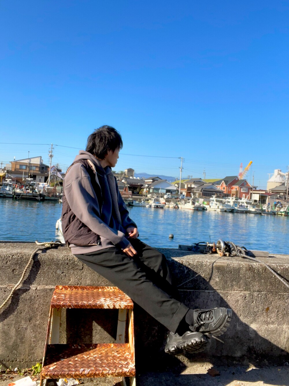 ブラック系のダウンベスト、グレー系のパーカー、ブラック系のその他パンツを着用したメンズの冬コーディネートの2枚目の写真