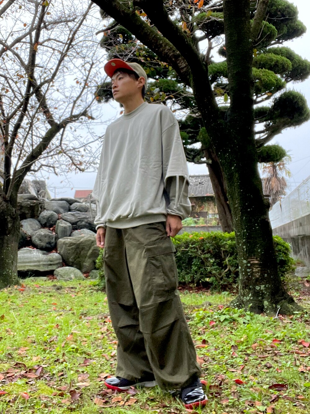 ベージュ系のスウェット、グリーン系のカーゴパンツ、ブラック系のスニーカーを着用したメンズの秋コーディネートの2枚目の写真