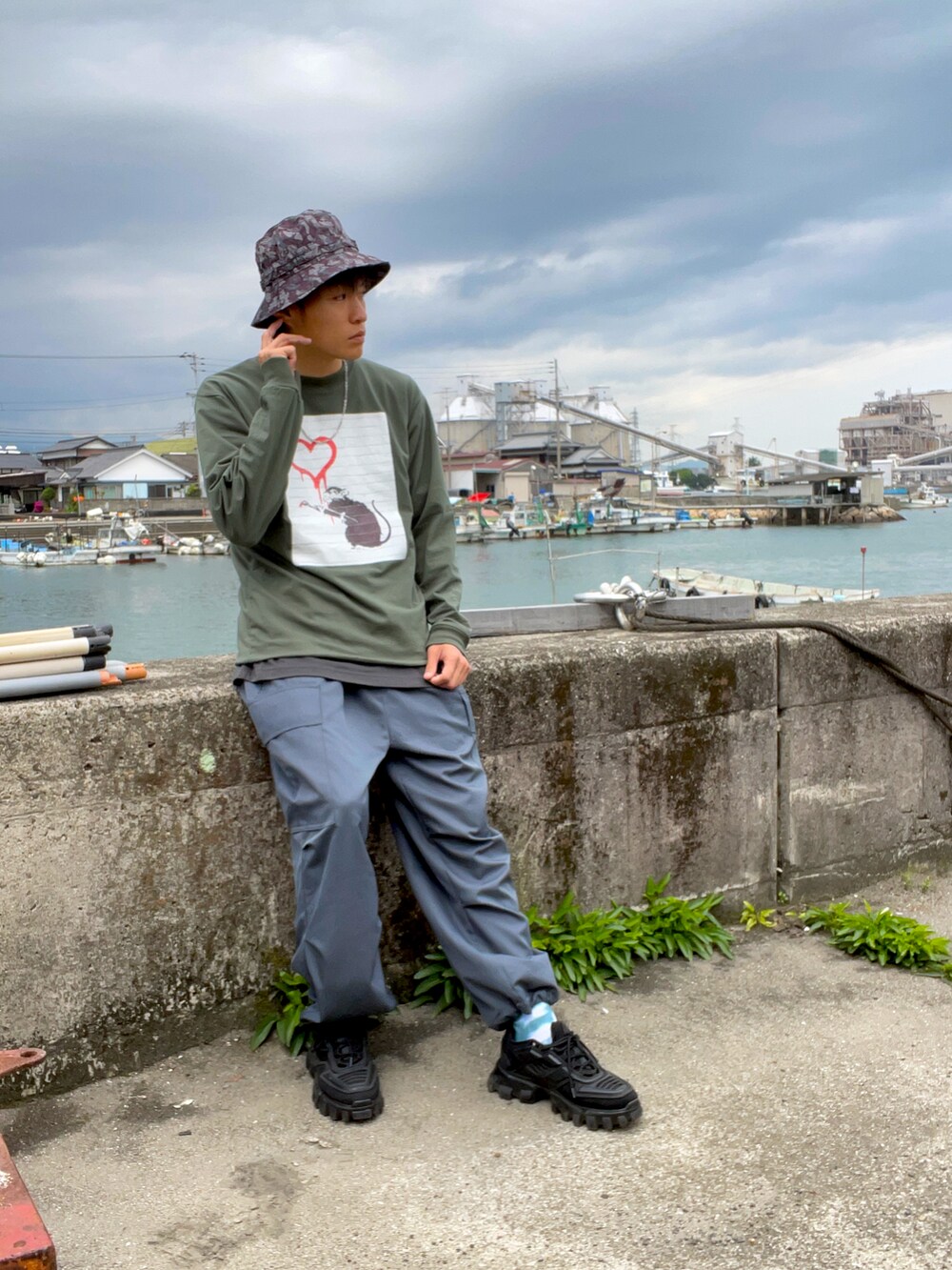 グリーン系のTシャツ/カットソー、グリーン系のカーゴパンツ、ブラック系のTシャツ/カットソーを着用したメンズの春コーディネートの2枚目の写真