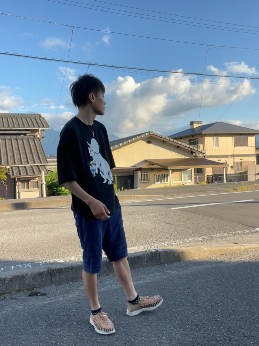 ブラック系のTシャツ/カットソー、ブルー系のパンツ、ブラウン系のサンダルを着用したメンズの夏コーディネートの2枚目の写真