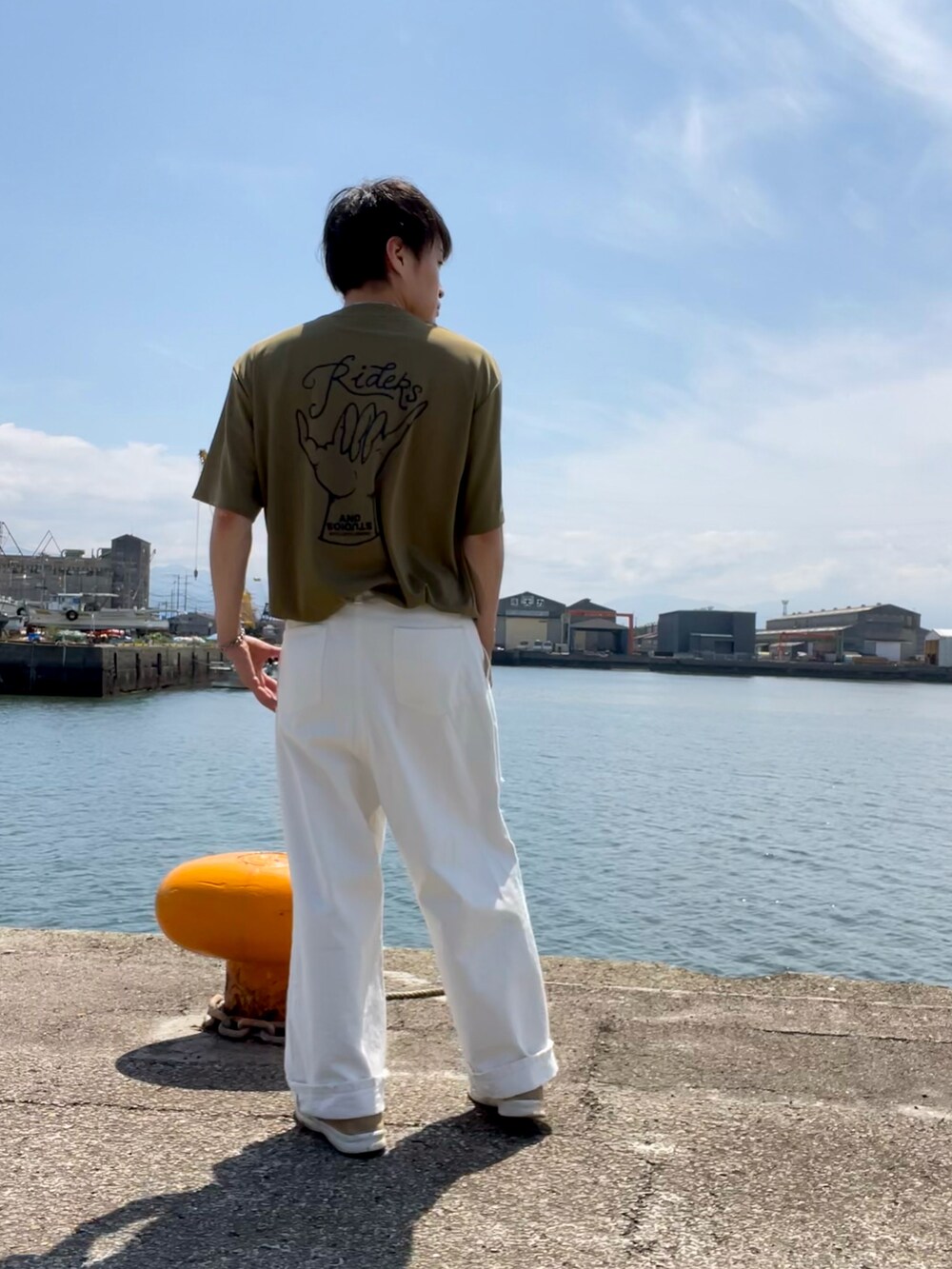 ホワイト系のデニムパンツ、ブラウン系のサンダル、グリーン系のTシャツ/カットソーを着用したメンズの夏コーディネートの2枚目の写真