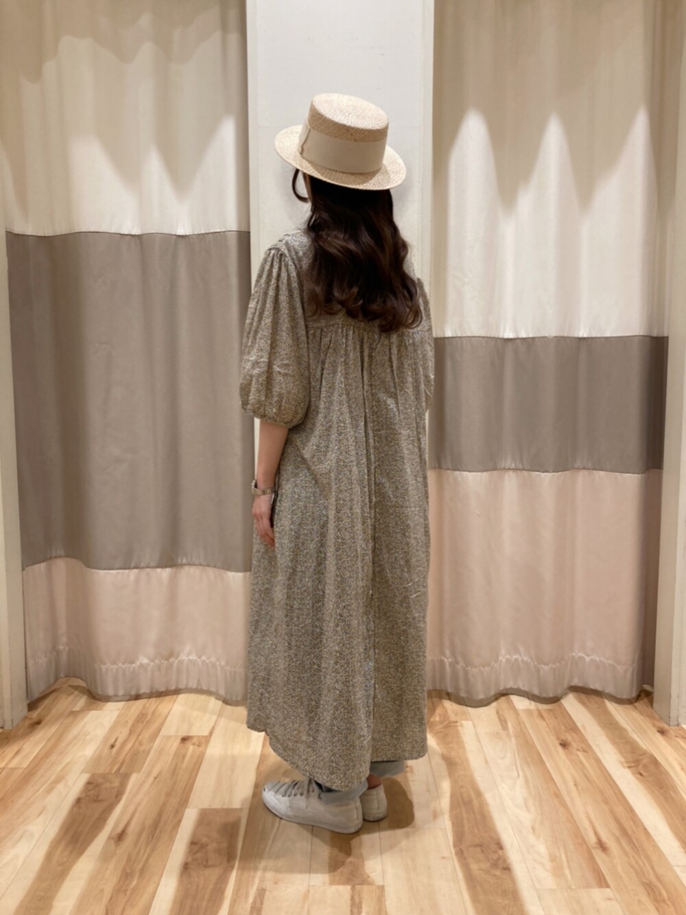 オレンジ系のワンピース、ホワイト系のハットを着用したレディースの春コーディネートの2枚目の写真