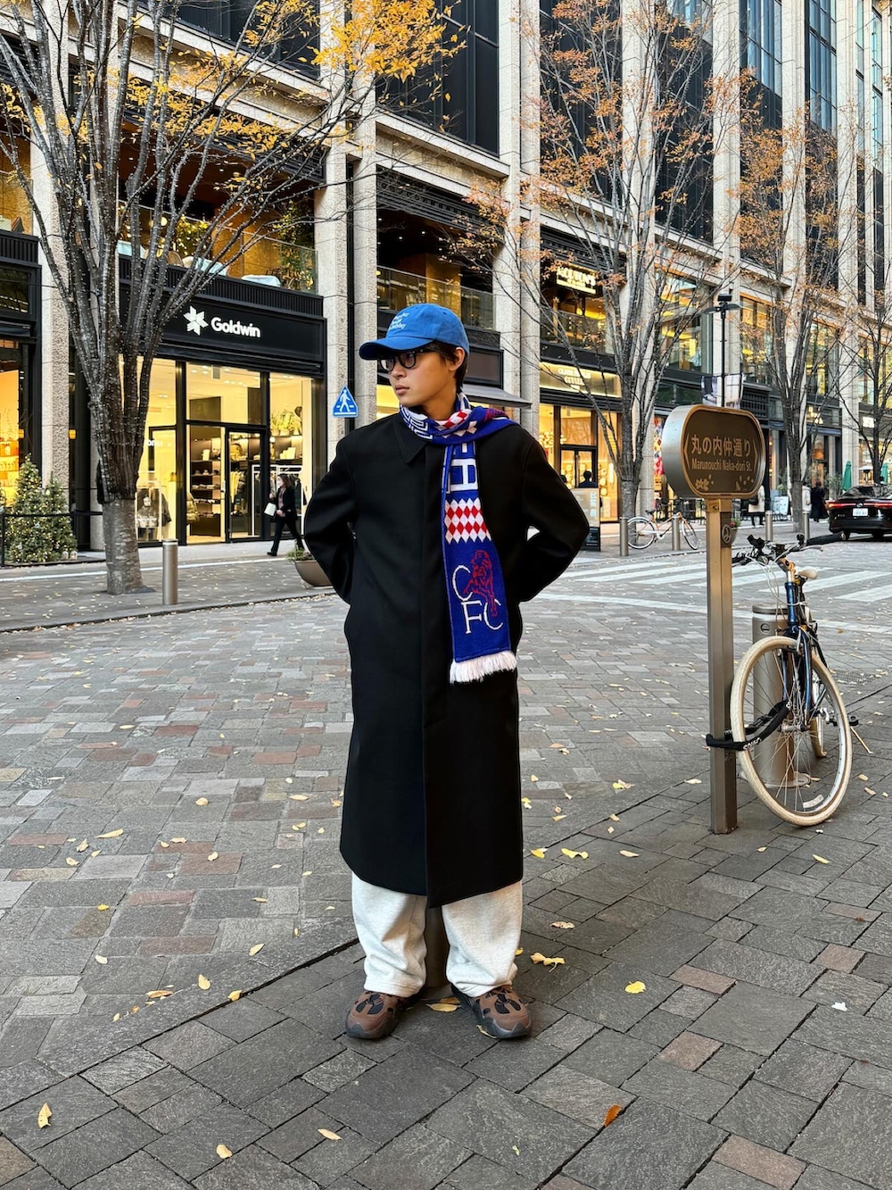 ブラック系のステンカラーコート、グレー系のスウェットパンツ、ブラウン系のスニーカーを着用したメンズの冬コーディネートの2枚目の写真