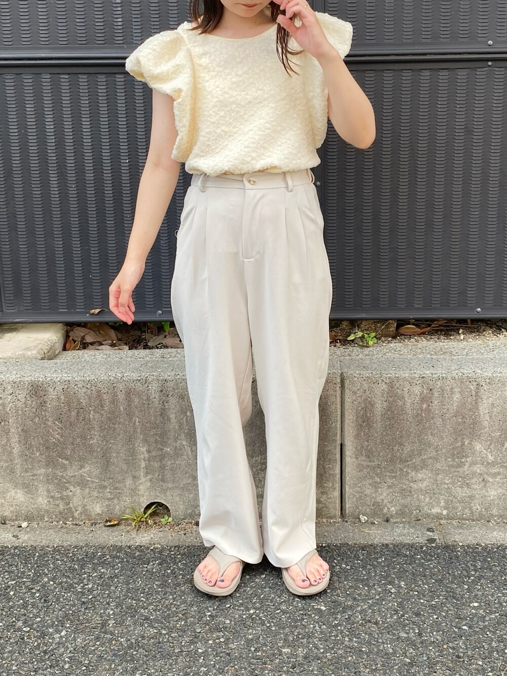 ホワイト系のTシャツ/カットソー、ベージュ系のサンダル、ホワイト系のスラックスを着用したレディースの夏コーディネートの2枚目の写真