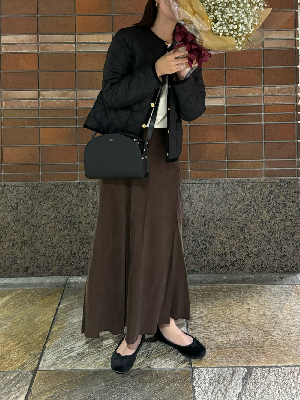 ブラック系のノーカラージャケット、ブラック系のショルダーバッグ、ブラウン系のスカートを着用したレディースの秋コーディネートの2枚目の写真
