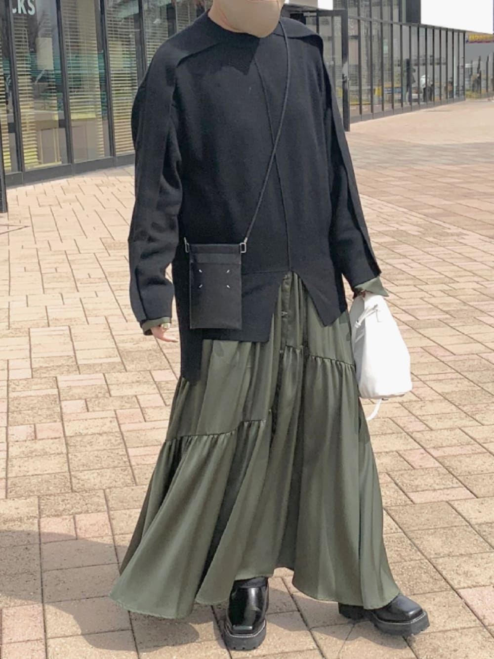 ブラック系のニット/セーター、グリーン系のワンピース、ブラック系のバッグを着用したレディースの春コーディネートの5枚目の写真