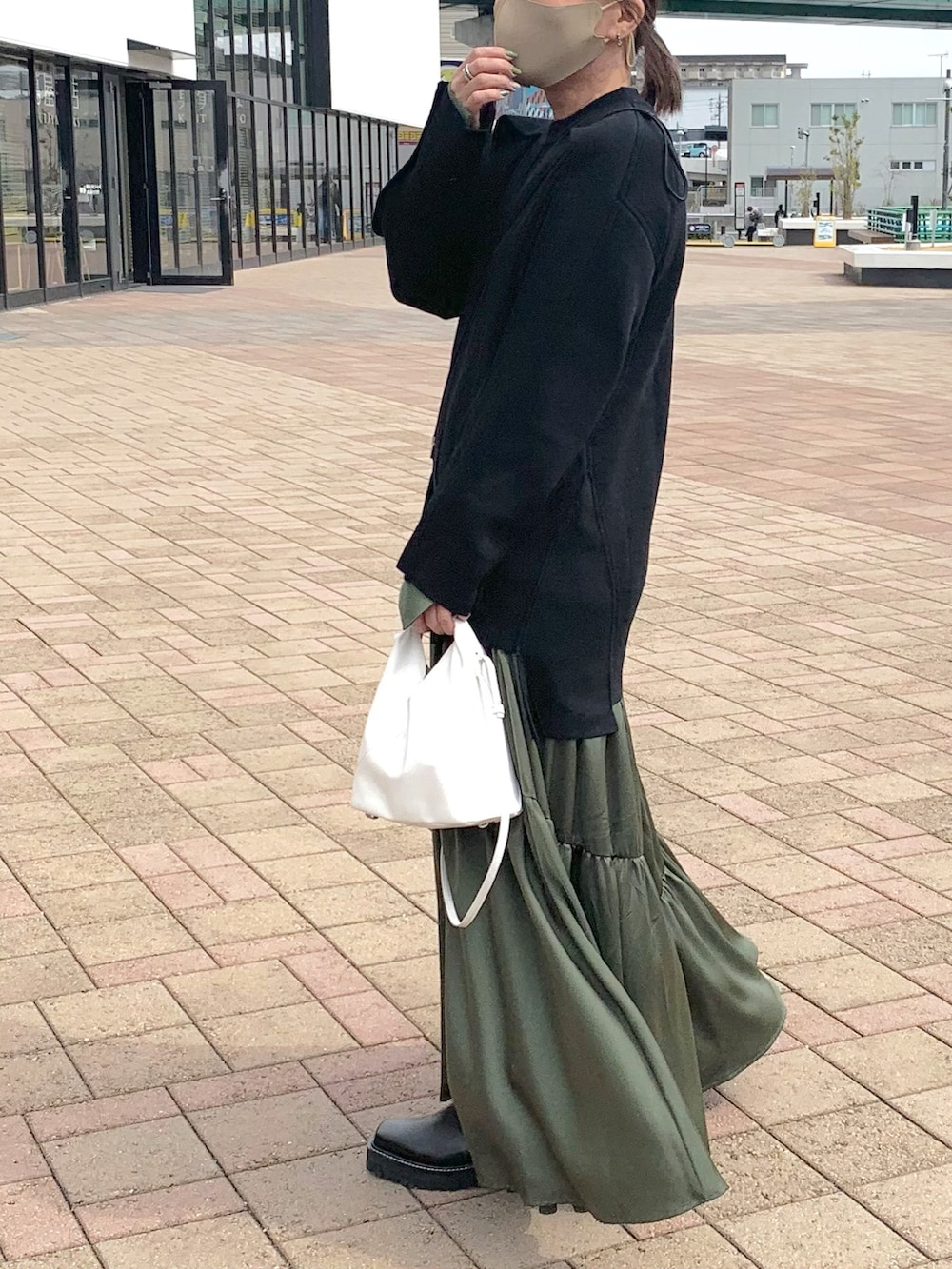 ブラック系のニット/セーター、グリーン系のワンピース、ブラック系のバッグを着用したレディースの春コーディネートの4枚目の写真