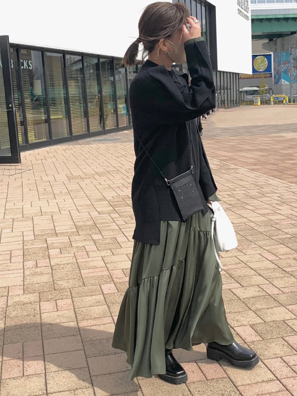 ブラック系のニット/セーター、グリーン系のワンピース、ブラック系のバッグを着用したレディースの春コーディネートの2枚目の写真