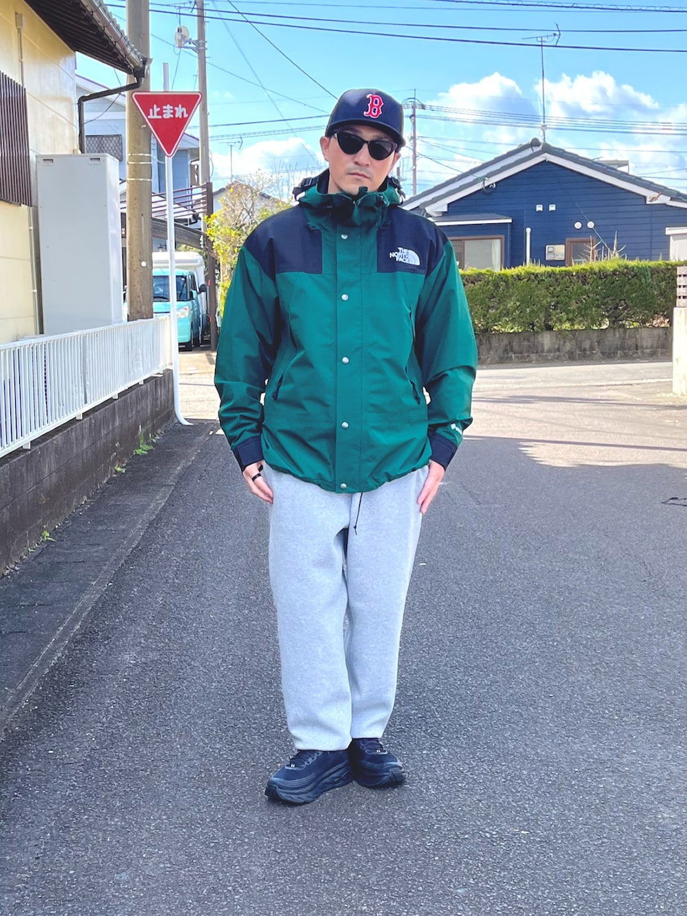 グリーン系のマウンテンパーカー、グレー系のスウェットパンツ、ブラック系のスニーカーを着用したメンズの冬コーディネートの2枚目の写真