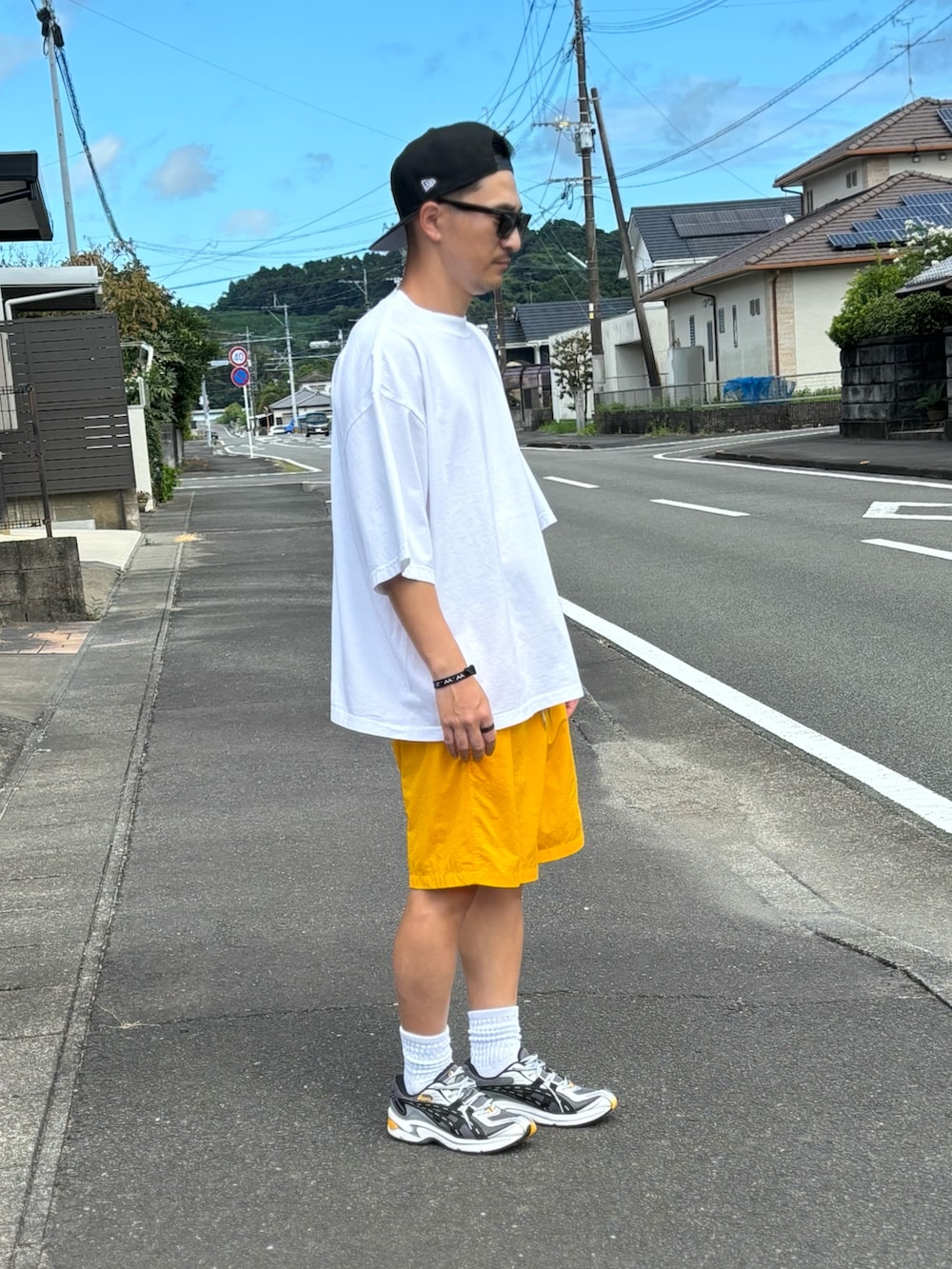 ブラック系のTシャツ/カットソー、イエロー系のパンツ、シルバー系のスニーカーを着用したメンズの秋コーディネートの2枚目の写真