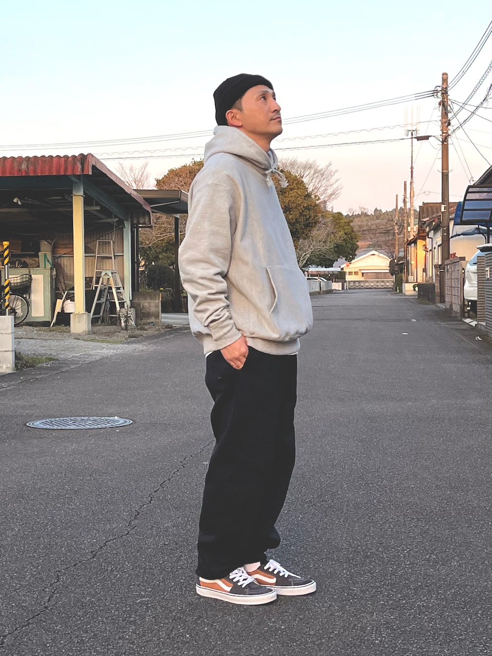 グレー系のパーカー、ブラック系のスウェットパンツ、オレンジ系のスニーカーを着用したメンズの春コーディネートの3枚目の写真