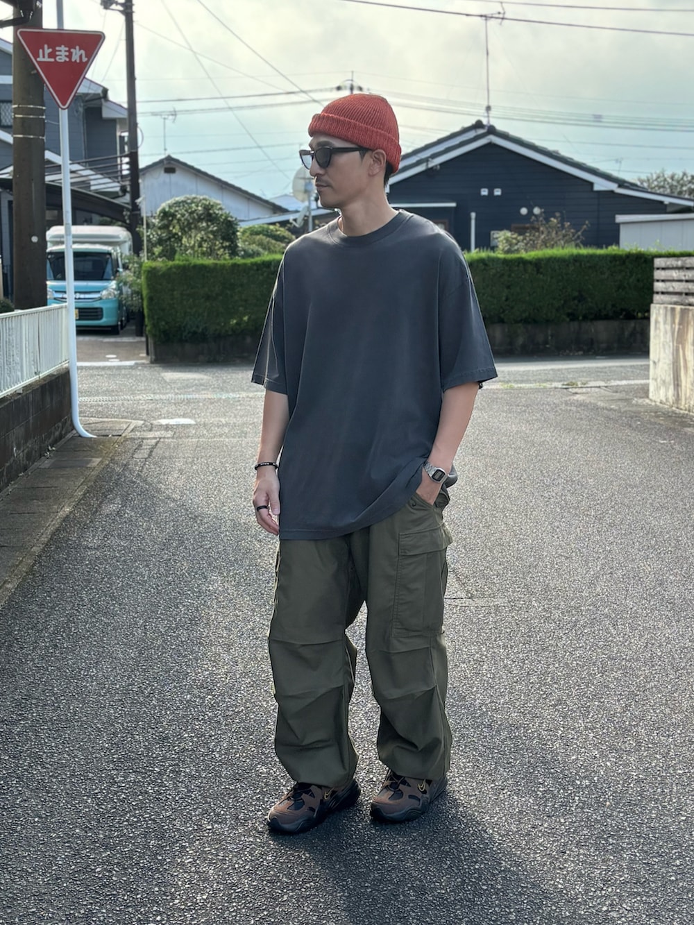ブラック系のTシャツ/カットソー、グリーン系のカーゴパンツ、ブラウン系のスニーカーを着用したメンズの秋コーディネートの2枚目の写真
