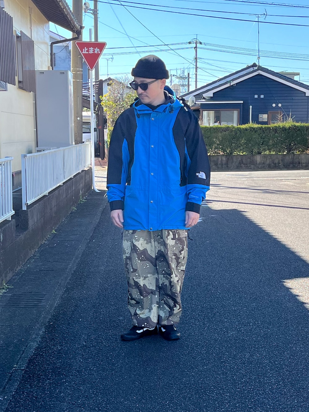 ブラック系のマウンテンパーカー、ベージュ系のカーゴパンツ、ブラック系のスニーカーを着用したメンズの春コーディネートの3枚目の写真