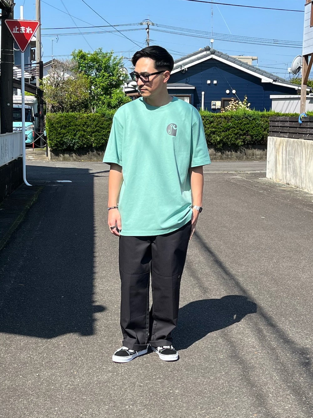 グリーン系のTシャツ/カットソー、グレー系のチノパンツ、ブラック系のスニーカーを着用したメンズの春コーディネートの2枚目の写真