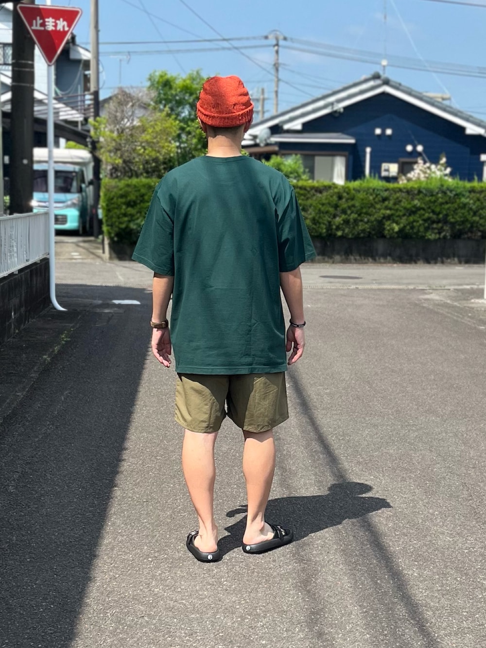 グリーン系のTシャツ/カットソー、ブラウン系のパンツ、ブラック系のサンダルを着用したメンズの春コーディネートの3枚目の写真