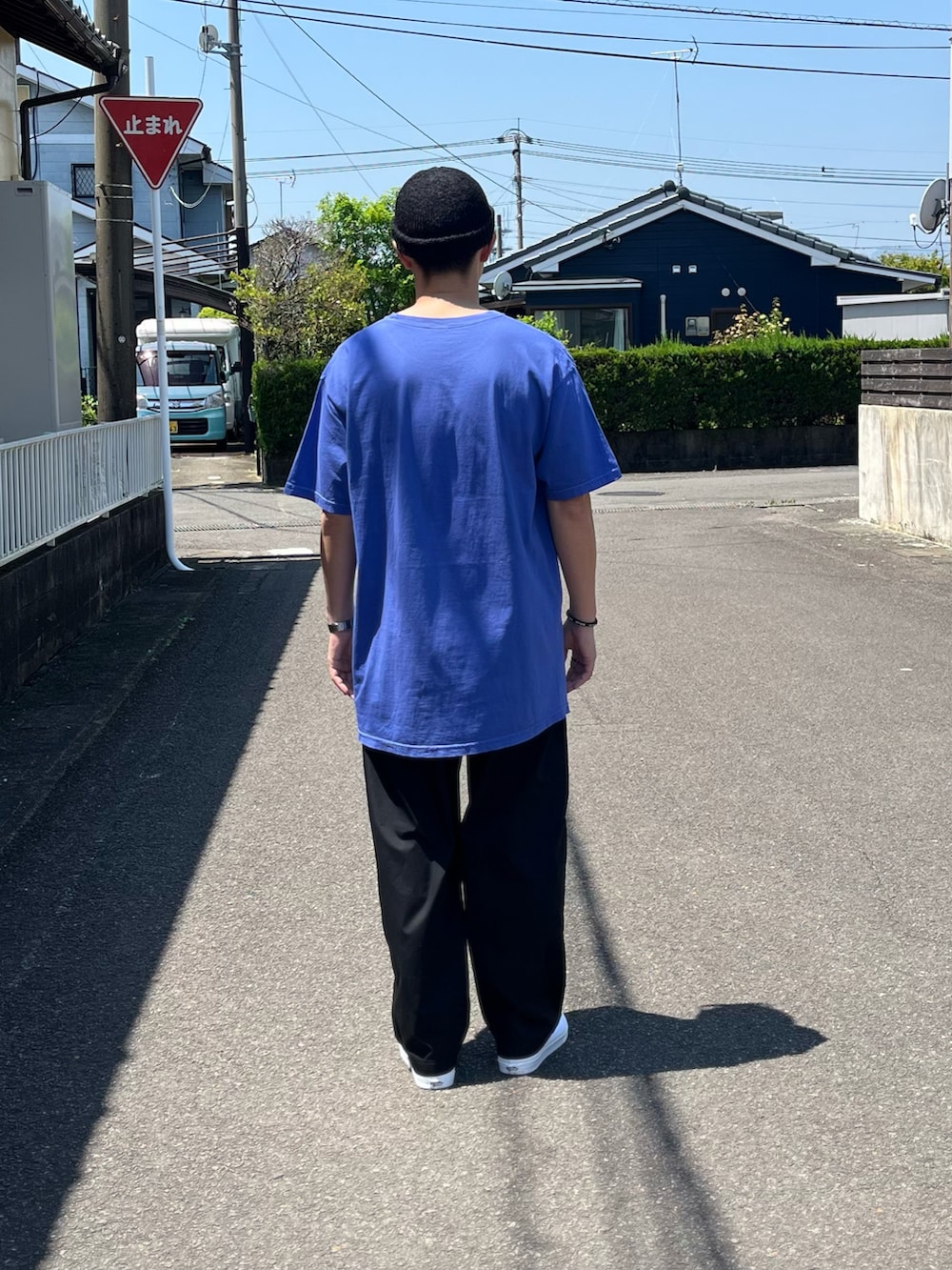 ブルー系のTシャツ/カットソー、ブラック系のパンツ、ホワイト系のスニーカーを着用したメンズの春コーディネートの3枚目の写真