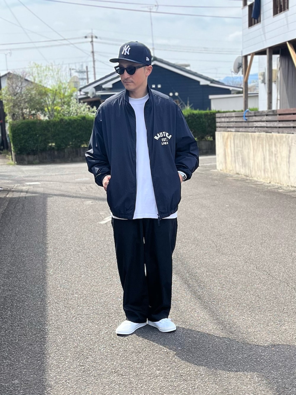 ブルー系のブルゾン、ホワイト系のTシャツ/カットソー、ブラック系のパンツを着用したメンズの春コーディネートの2枚目の写真