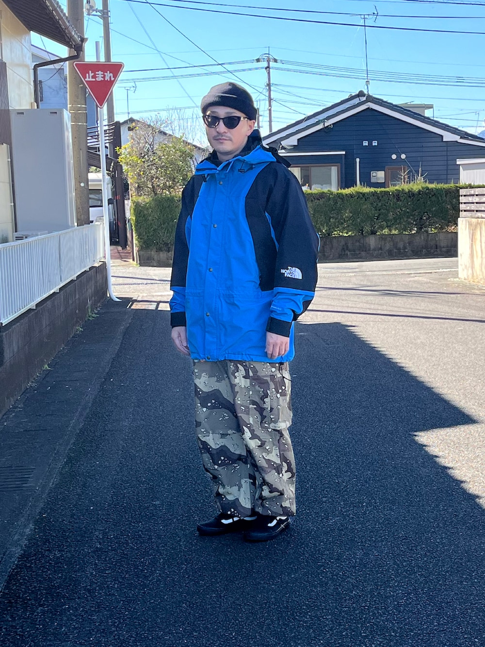 ブラック系のマウンテンパーカー、ベージュ系のカーゴパンツ、ブラック系のスニーカーを着用したメンズの春コーディネートの2枚目の写真