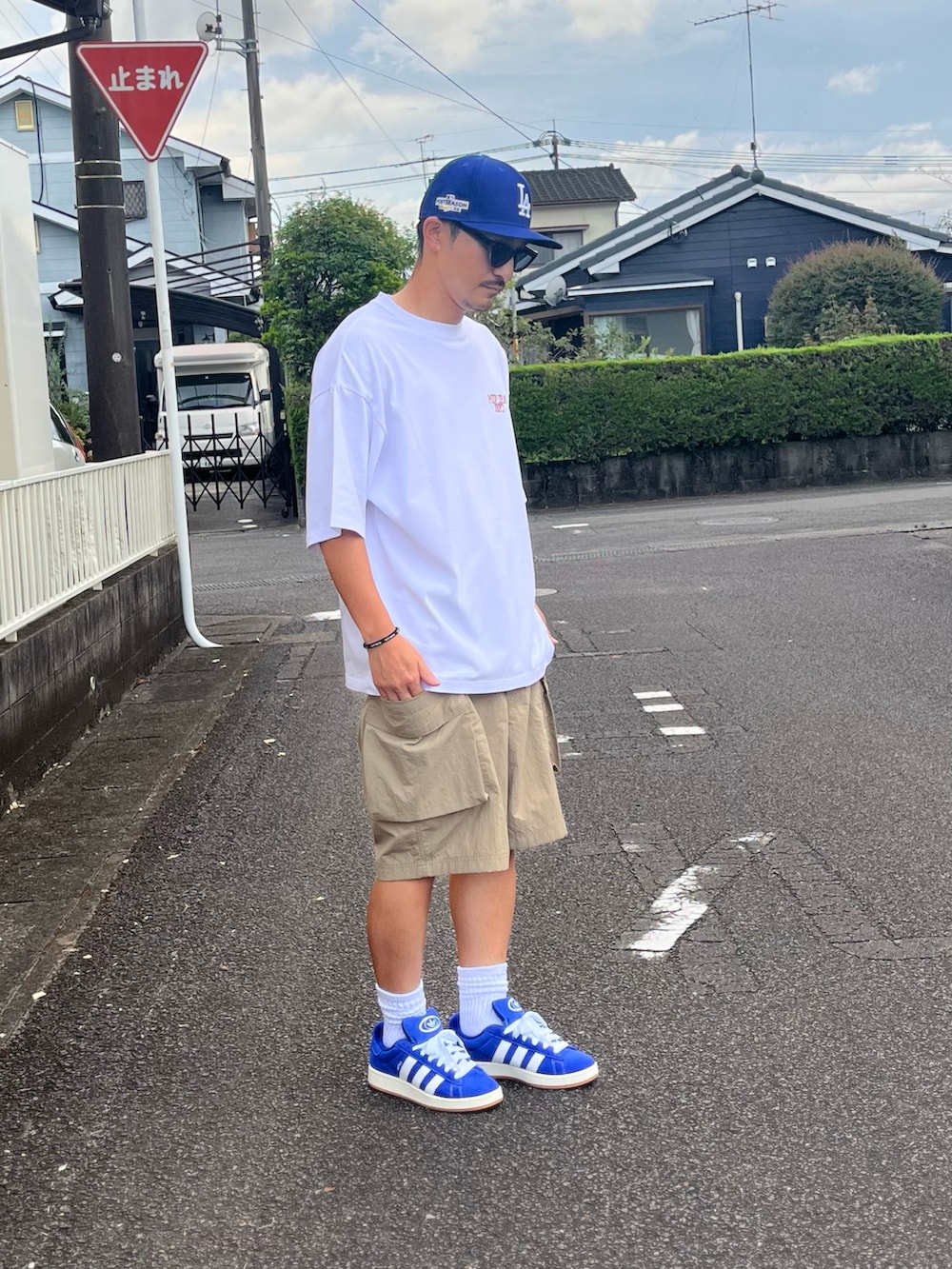 ホワイト系のTシャツ/カットソー、ベージュ系のカーゴパンツ、ブルー系のスニーカーを着用したメンズの秋コーディネートの2枚目の写真