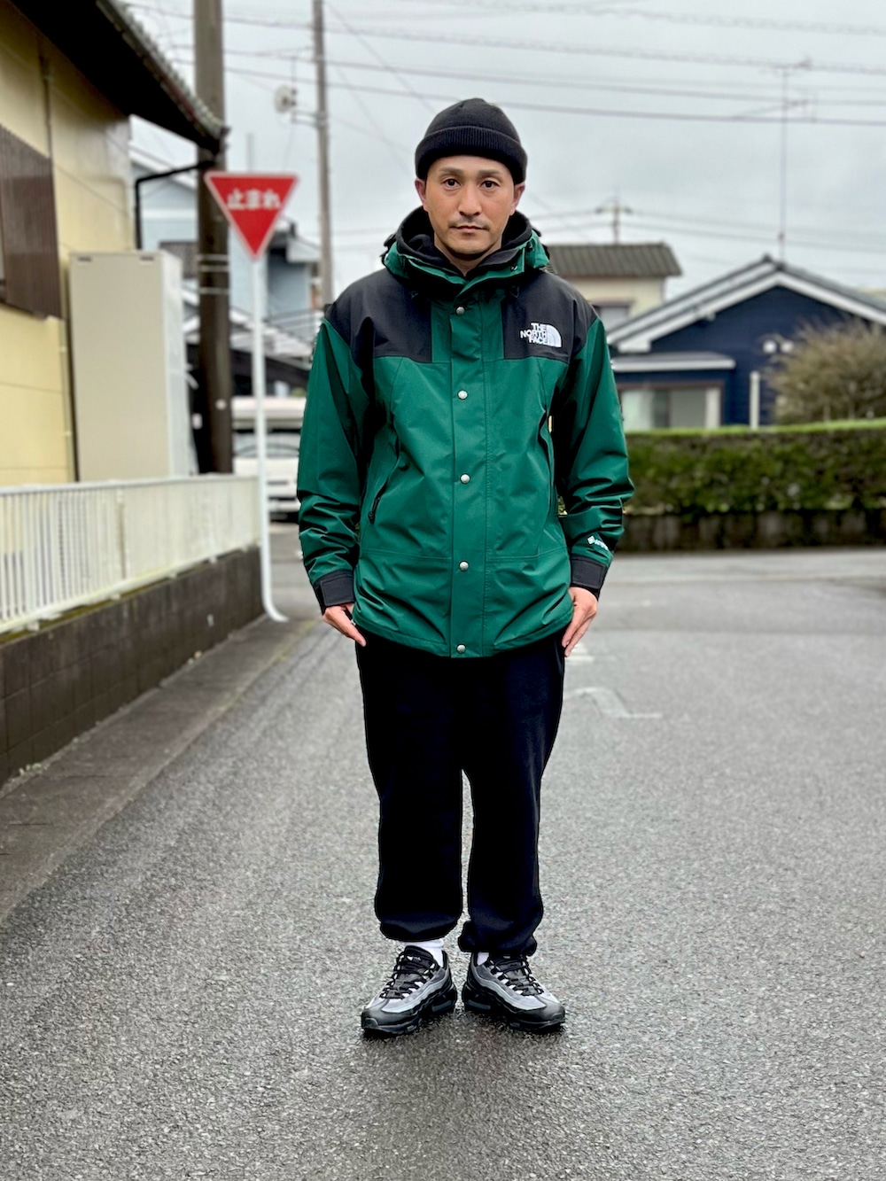グリーン系のマウンテンパーカー、ブラック系のスウェットパンツ、ブラック系のスニーカーを着用したメンズの冬コーディネートの3枚目の写真