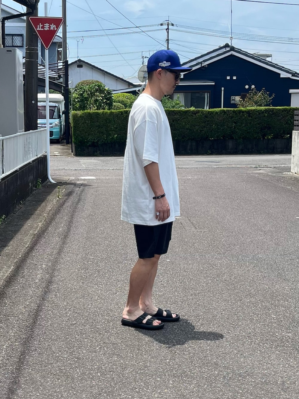 ブラック系のサンダル、ホワイト系のTシャツ/カットソー、ブルー系のその他パンツを着用したメンズの夏コーディネートの3枚目の写真