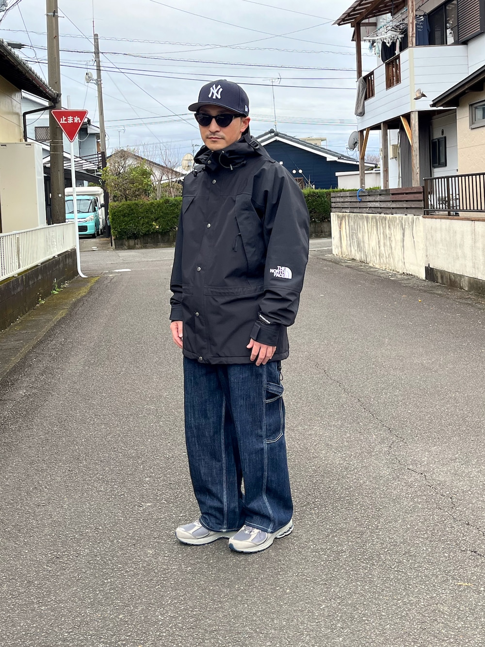 ブラック系のマウンテンパーカー、ブルー系のデニムパンツ、グレー系のスニーカーを着用したメンズの冬コーディネートの3枚目の写真