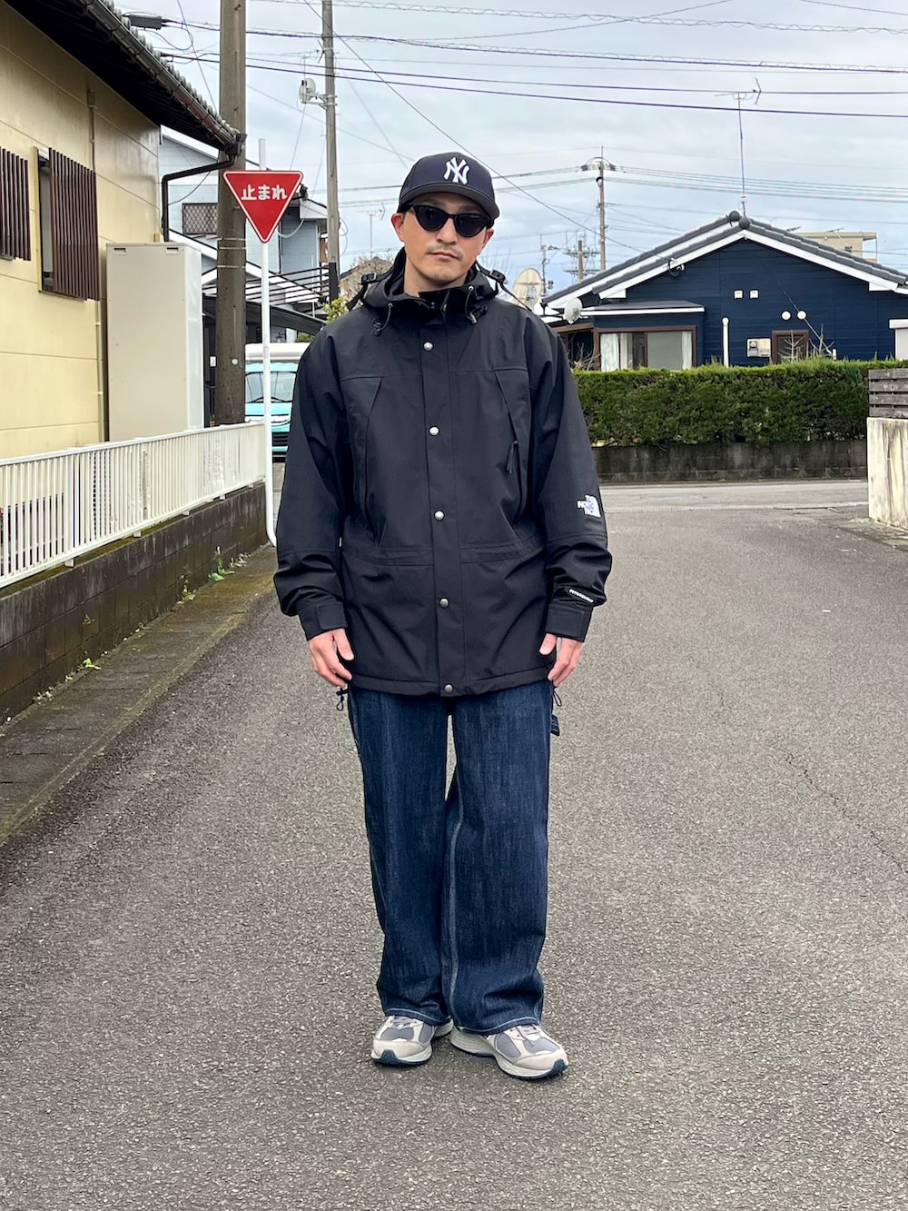 ブラック系のマウンテンパーカー、ブルー系のデニムパンツ、グレー系のスニーカーを着用したメンズの冬コーディネートの2枚目の写真