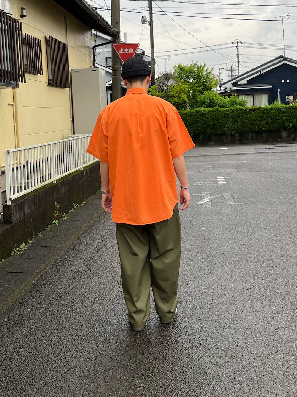 オレンジ系のシャツ/ブラウス、グリーン系のチノパンツ、ブラック系のスニーカーを着用したメンズの春コーディネートの3枚目の写真
