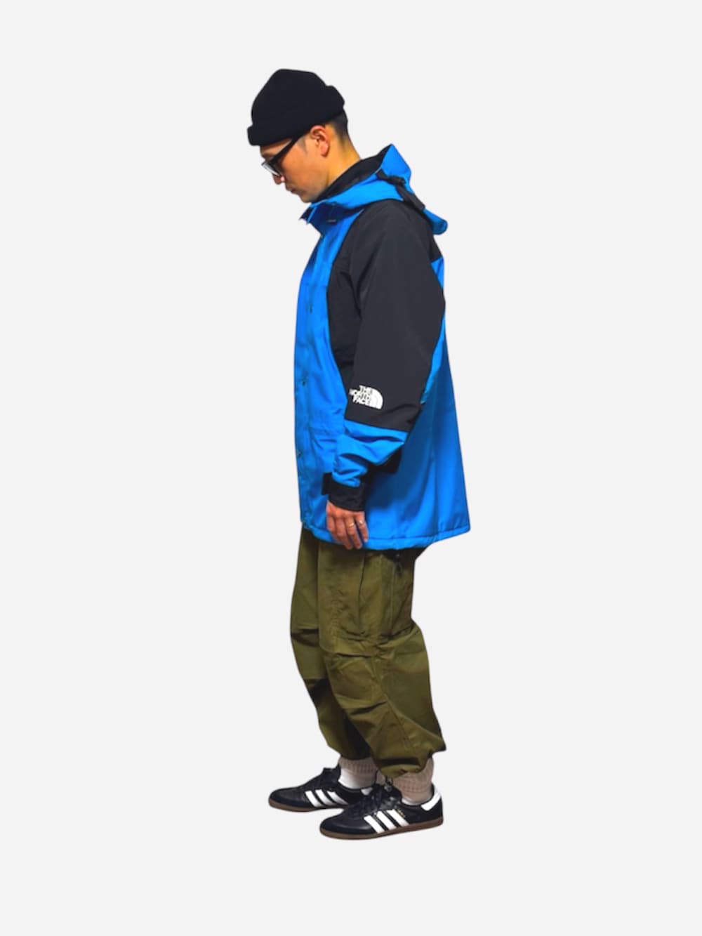 ブラック系のスニーカー、ブルー系のマウンテンパーカー、グリーン系のカーゴパンツを着用したメンズの冬コーディネートの2枚目の写真