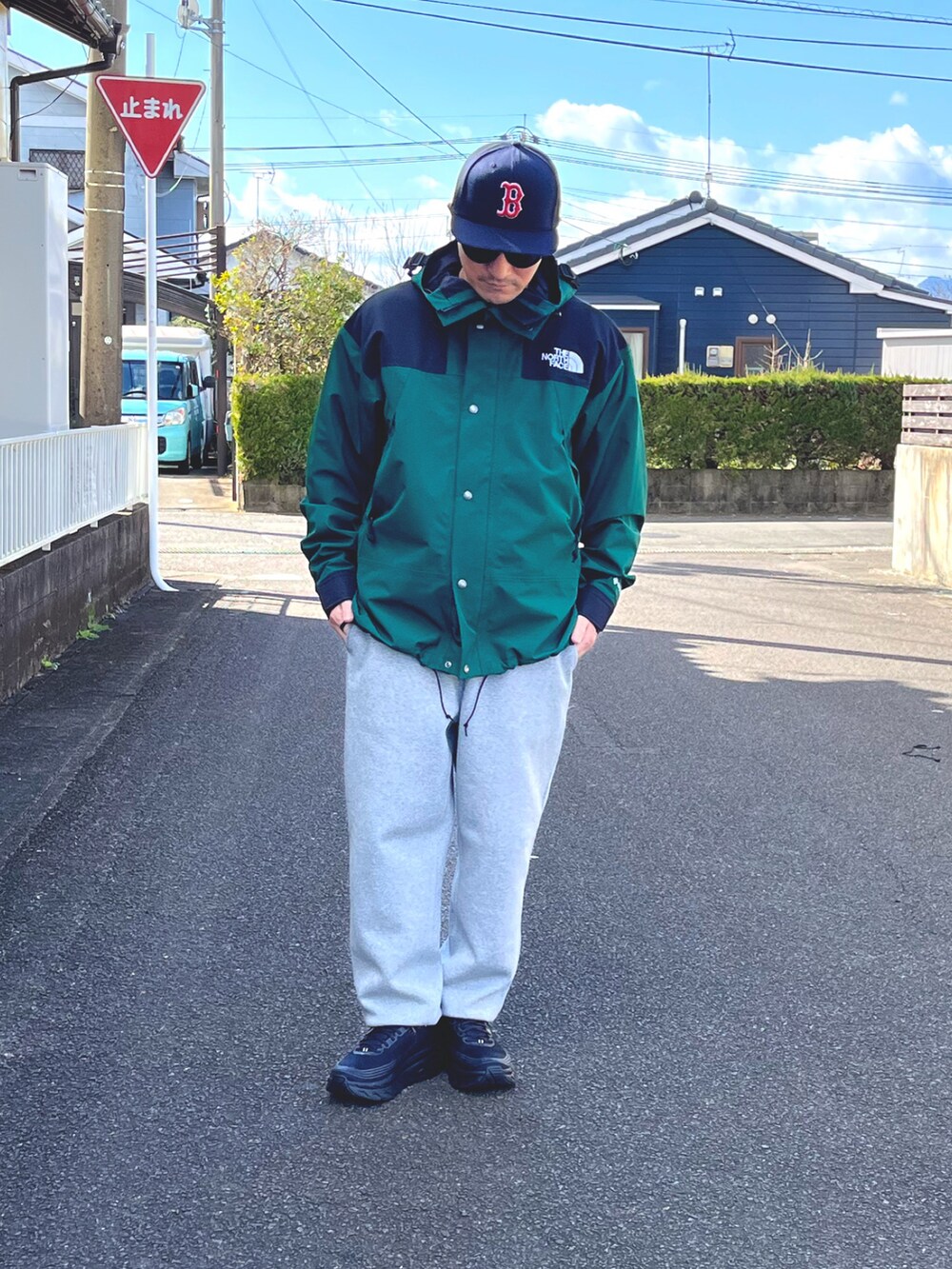 グリーン系のマウンテンパーカー、グレー系のスウェットパンツ、ブラック系のスニーカーを着用したメンズの冬コーディネートの4枚目の写真
