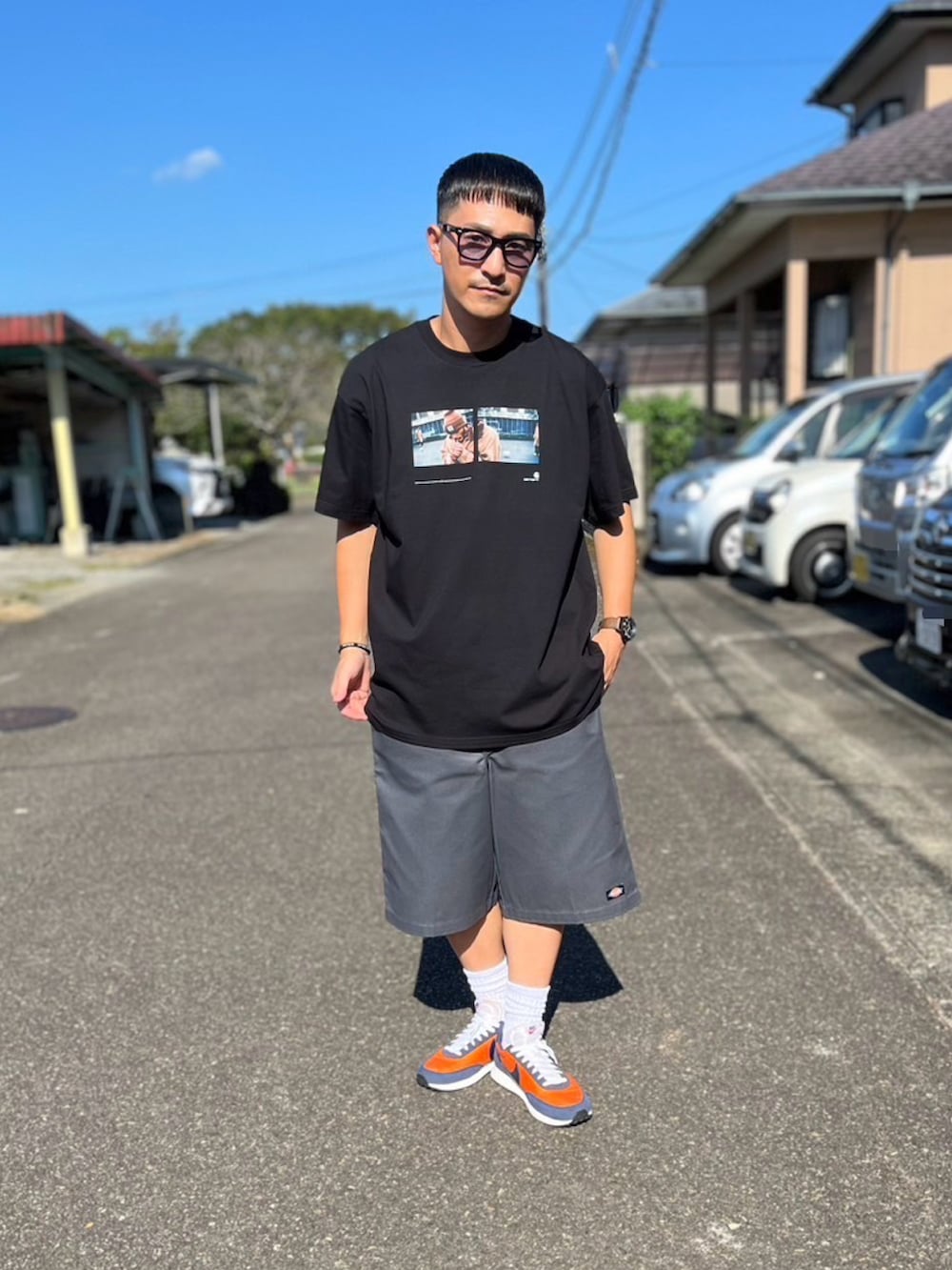 ブラック系のTシャツ/カットソー、ブラック系のチノパンツ、オレンジ系のスニーカーを着用したメンズの秋コーディネートの2枚目の写真