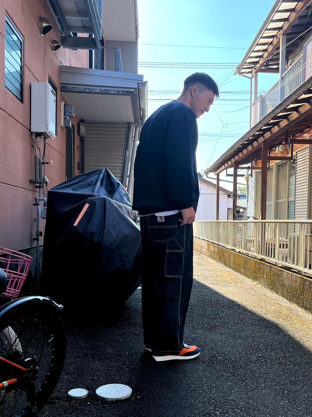 ブルー系のスウェット、ブルー系のデニムパンツ、オレンジ系のスニーカーを着用したメンズの秋コーディネートの3枚目の写真