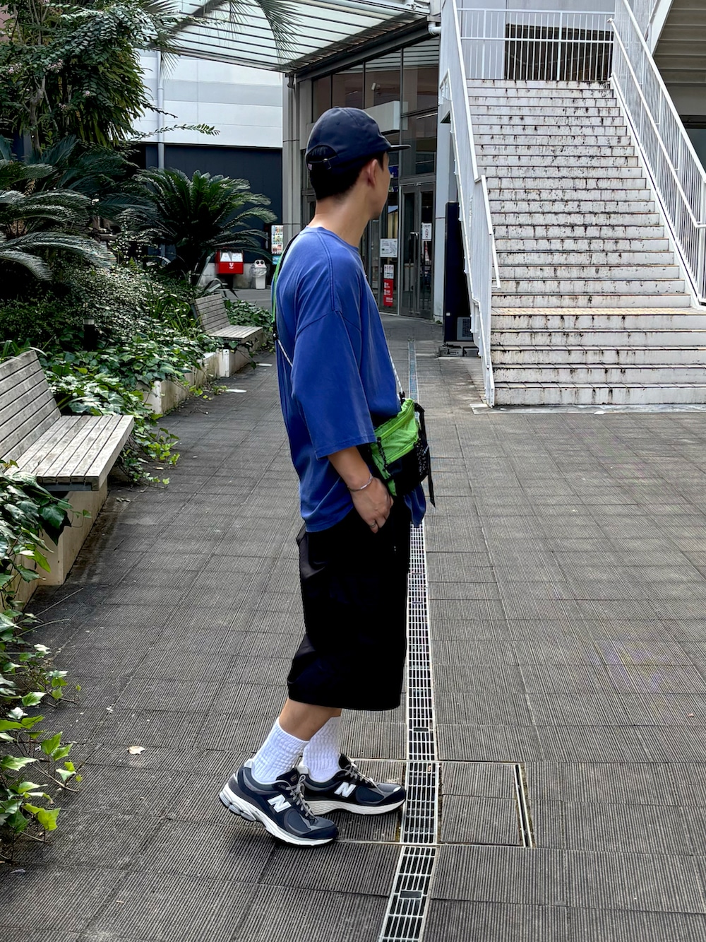ブルー系のTシャツ/カットソー、ブラック系のパンツ、グリーン系のショルダーバッグを着用したメンズの夏コーディネートの2枚目の写真