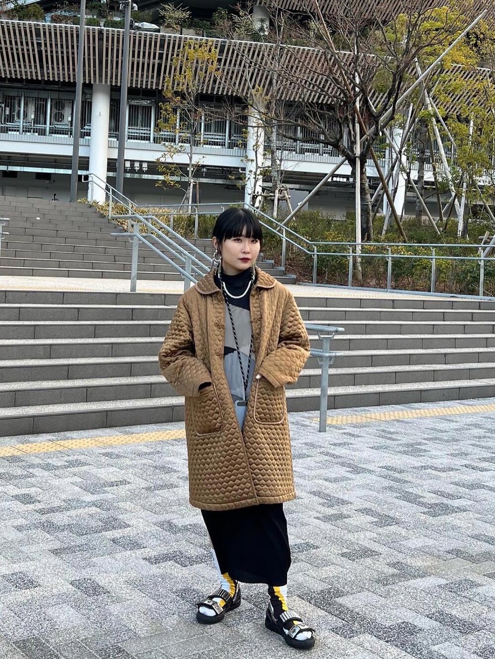 ブラック系のワンピース/ドレス、ゴールド系のジャケット/アウター、ブラック系のサンダルを着用したレディースの冬コーディネートの2枚目の写真